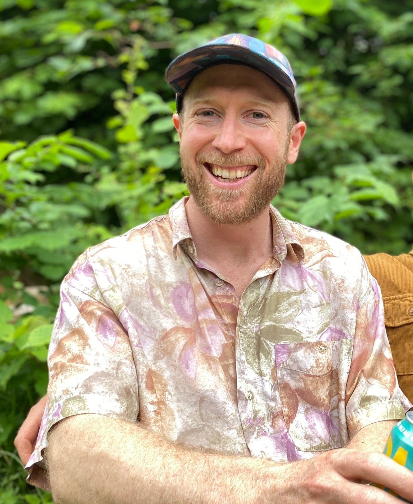 Andy Sontag smiling outdoors in a patterned shirt and cap